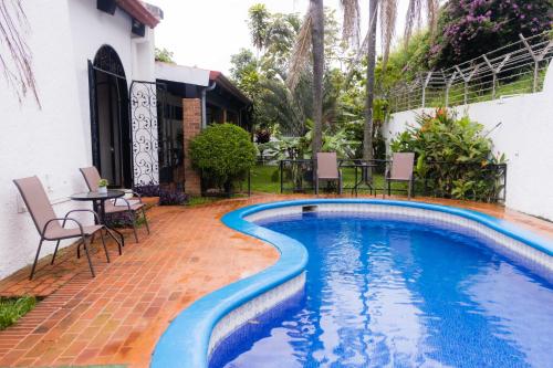 a swimming pool with chairs and a table next to a house at Hotel Casona del Valle in Potrerillos