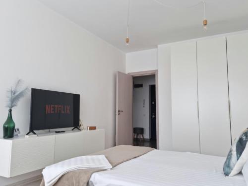 a white bedroom with a bed and a tv on a cabinet at Studio Nova - Minimalist and Elegant with Parking in Bucharest