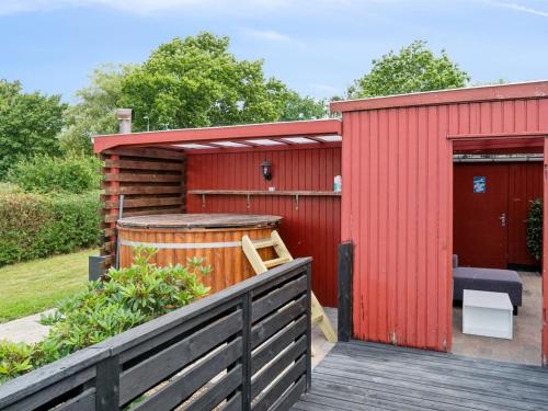 レネにあるHoliday Home Simon - 1km from the sea by Interhomeの温水浴槽と木製のデッキを備えた赤い小屋