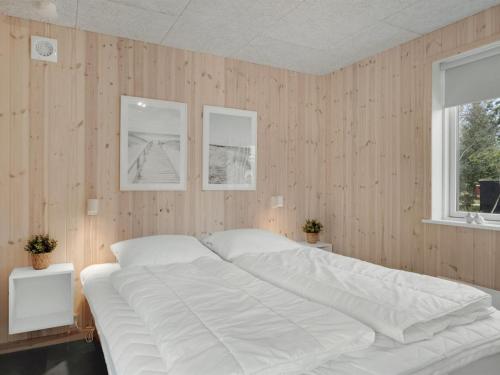 a large white bed in a room with wooden walls at Holiday Home Onni - 2-3km from the sea by Interhome in Saltum