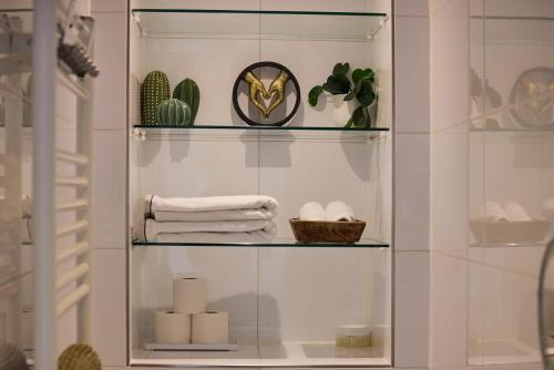 estante de cristal en el baño con toallas y plantas en Treehouse Inn, en Duivendrecht