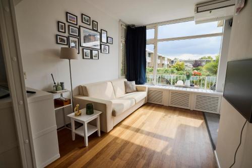 Una sala de estar con un sofá blanco y una ventana grande. en Treehouse Inn, en Duivendrecht