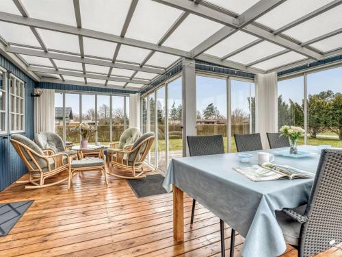a conservatory with a table and chairs and windows at Holiday Home Thorir - 500m from the sea by Interhome in Dannemare