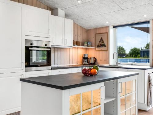 a kitchen with white cabinets and a black counter top at Holiday Home Helmtrud - 700m from the sea by Interhome in Neder Lysabild