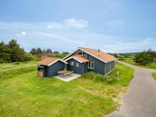 a blue house on the side of a grass field at Holiday Home Felicita - from the sea by Interhome in Ulfborg