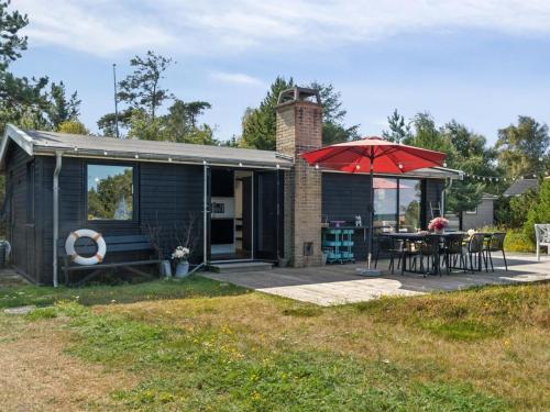a small house with a patio with a table and an umbrella at Holiday Home Kaj - 75m from the sea by Interhome in Tjørneholm