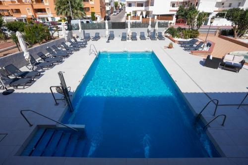 an empty swimming pool with chairs and blue water at Hospedium Hotel Continental in Mojácar