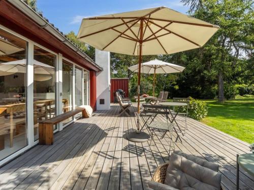 a wooden deck with a table and an umbrella at Holiday Home Lauri - 2-3km from the sea by Interhome in Vejby