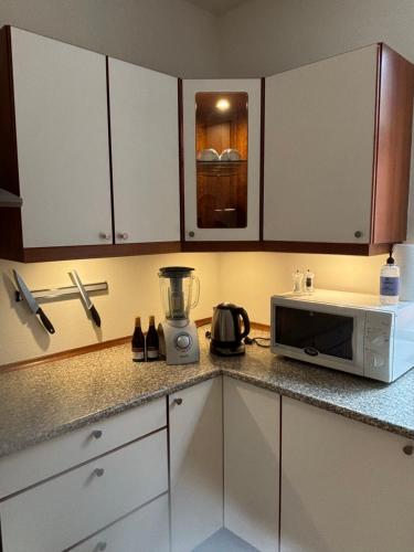 a kitchen with white cabinets and a microwave on a counter at Lejlighed Østergade Herning in Herning