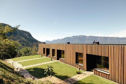 a wooden house with a garden and mountains in the background at Hochegg Hideaway in Laives