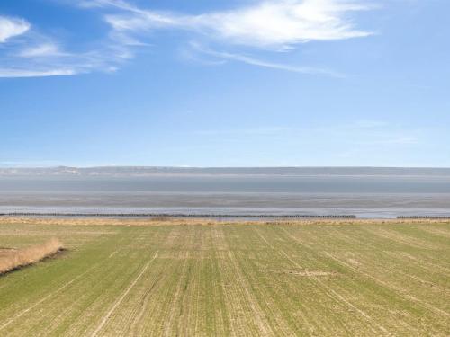 a field of grass with the ocean in the background at Holiday Home Freja - 12km from the sea by Interhome in Bredebro