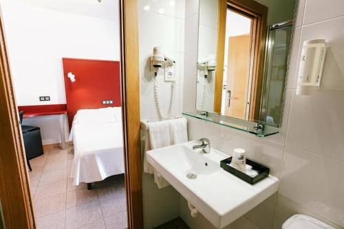 a bathroom with a sink and a mirror and a bed at Hospedium Hotel Continental in Mojácar