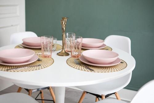 a white table with pink plates and glasses on it at Suite Deluxe royauté Jacuzzi, Mulhouse Centre in Mulhouse