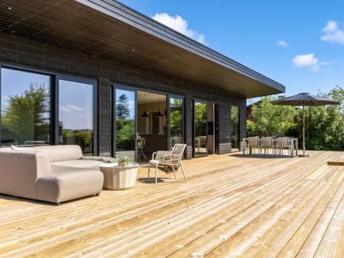 a wooden deck with a couch and chair on a house at Holiday Home Edvia - 200m to the fjord by Interhome in Holbæk