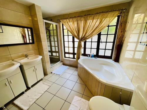 a bathroom with a tub and a sink and a toilet at Pretoria Mansion Boutique Hotel Coral Tree in Pretoria