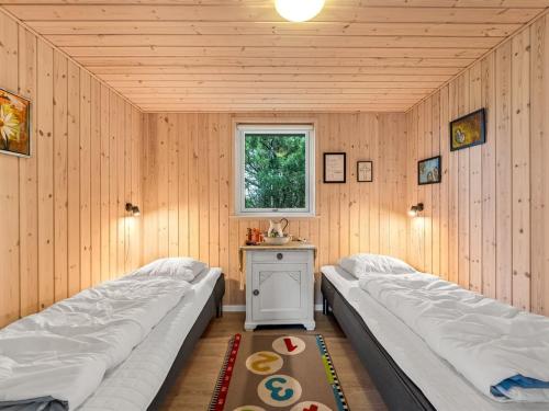 two beds in a room with a table and a window at Holiday Home Teija - 600m to the fjord by Interhome in Skjern