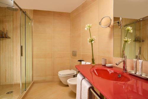 a bathroom with a red sink and a toilet at Il Boscareto Resort & Spa in Serralunga d'Alba