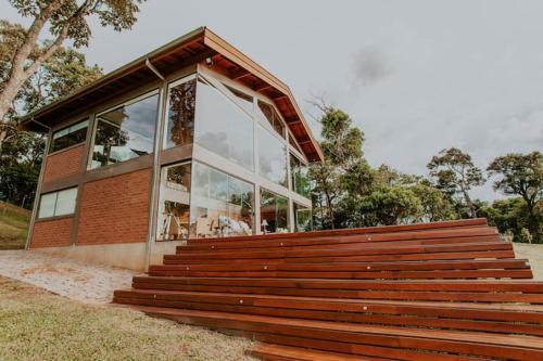 a building with a large window and a wooden bench at Chalet nas Nuvens with Infinity Pool in São Bento do Sapucaí