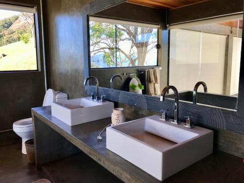 a bathroom with two sinks and a toilet at Chalet nas Nuvens with Infinity Pool in São Bento do Sapucaí