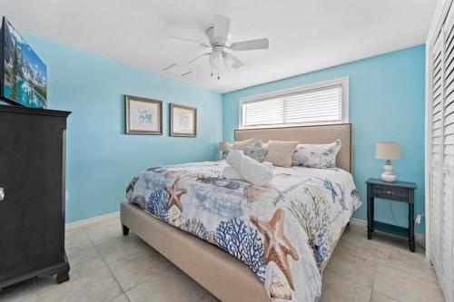 a blue bedroom with a bed and a ceiling fan at Ocean72 Holmes Beach Vacation Home with Private Pool & hot tub & Walk-to-Beach Access in Holmes Beach