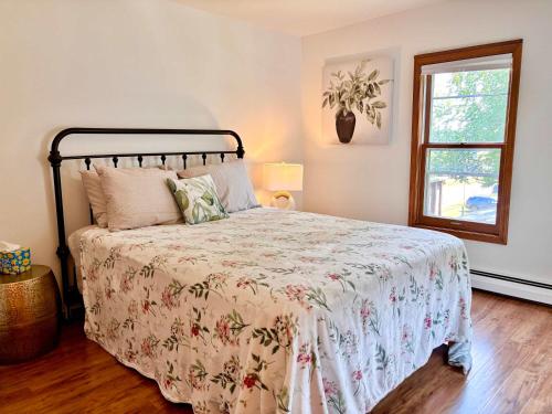 a bedroom with a bed with a floral bedspread and a window at Torch Lake Vista With Lake access in Rapid City
