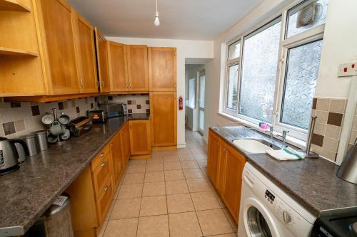 a kitchen with wooden cabinets and a washing machine at Cosy 3-Bed Swansea Home near City & Bay in Swansea