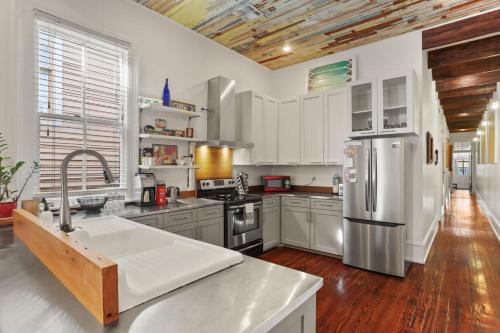 a kitchen with a stainless steel refrigerator and wooden floors at Heart of MidCity Front Porch 3bd 2 bath Streetcar in New Orleans