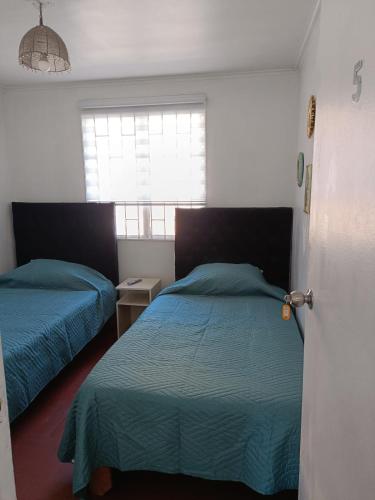 a bedroom with two beds and a window at Hotel del centro rancagua in Rancagua