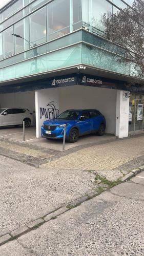 a blue car parked in a garage in front of a building at Hotel del centro rancagua in Rancagua