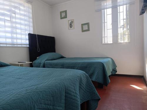 a bedroom with two beds and two windows at Hotel del centro rancagua in Rancagua