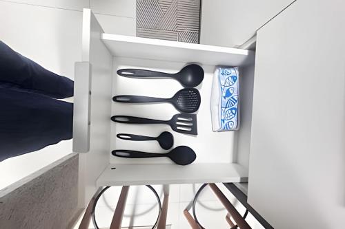 ein weißer Schrank mit schwarzen Küchenutensilien darin in der Unterkunft 809 Studio Ideal for Vacation and Business Sea View in Salvador