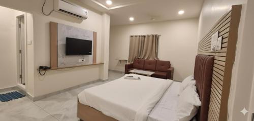 a bedroom with a bed and a chair and a television at Hotel JK Height's Miyapur, Near Lingampally Railway Station in Lingampalli