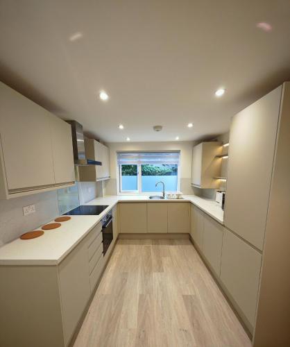 a kitchen with white cabinets and a sink and a window at Cozy corner 2 bedroom house in Edinburgh