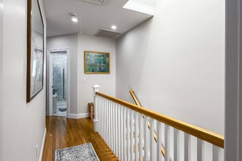 a hallway with a staircase with white walls and wood floors at Hillside's Setting Sun Waterfront Retreat in Milford