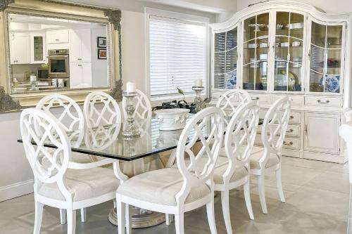 a dining room with a glass table and white chairs at Hillside's Setting Sun Waterfront Retreat in Milford