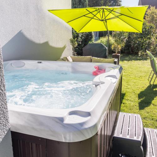 a hot tub with an umbrella in a yard at Casa Cambodunum in Kempten