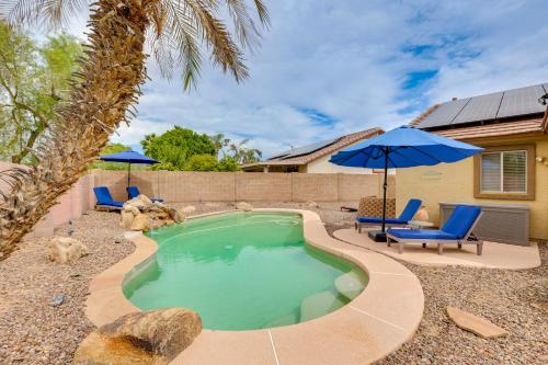 a swimming pool with chairs and an umbrella at Spacious and Fenced Yard Pet-Friendly Surprise Home in Surprise