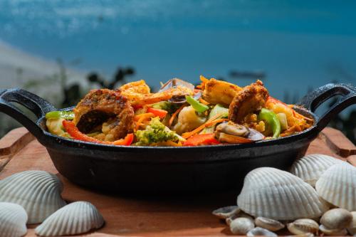 a bowl of food sitting on a table with shells at Soledade Bangalôs - Kauli Seadi in Macau