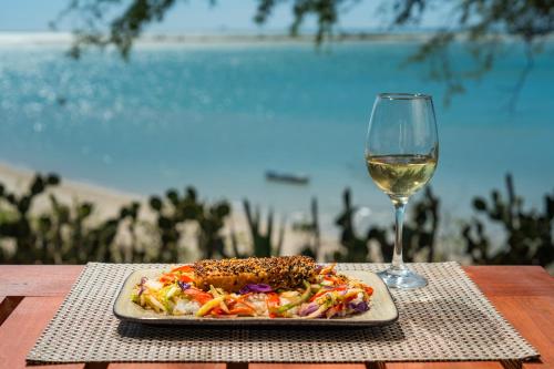 a plate of food next to a glass of wine at Soledade Bangalôs - Kauli Seadi in Macau