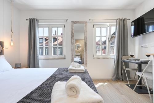 a bedroom with a bed and a desk and windows at Largo da Praça Boutique by Sé Apartamentos in Braga
