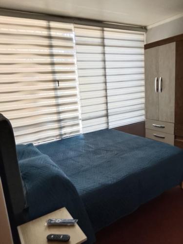 a bedroom with a blue bed and a table at Hotel del centro rancagua in Rancagua