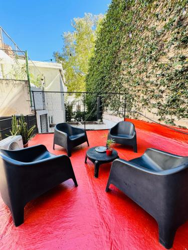a group of chairs and tables on a red rug at Lacandona Hostel in Cordoba
