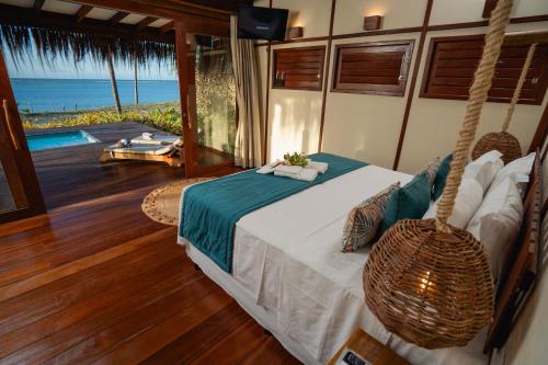 a bedroom with a swinging bed with a view of the ocean at Soledade Bangalôs - Kauli Seadi in Macau