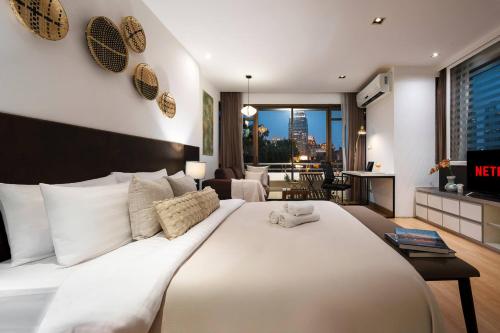 a bedroom with a large white bed and a living room at Quiet Asoke/Nana BTS Retreat w/ Skyline & Gym/Park in Bang Kapi