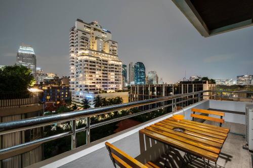 a balcony with a wooden bench and a city skyline at Quiet Asoke/Nana BTS Retreat w/ Skyline & Gym/Park in Bang Kapi