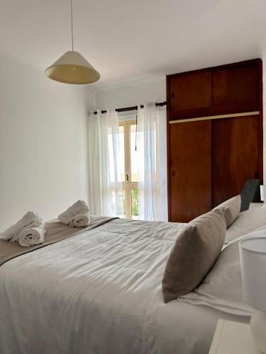 a bedroom with a large white bed with a wooden headboard at Ohana Funchal in Funchal
