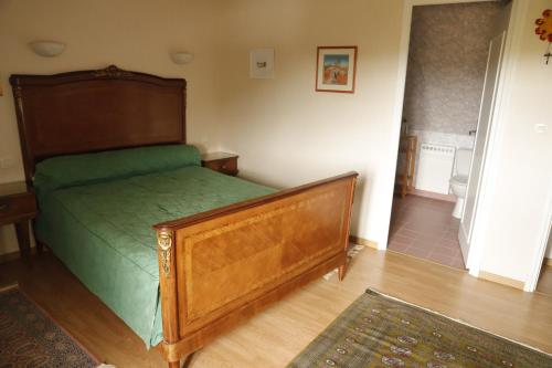 a bedroom with a wooden bed with a green sheets at Bair Nestad in Assigny