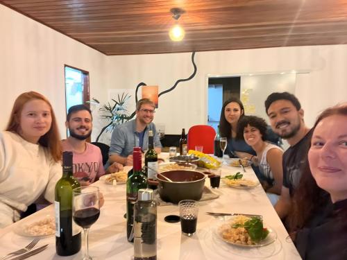 a group of people sitting around a table with wine bottles at Nômades Riverside - Adventure Hostels & Coworking in Florianópolis