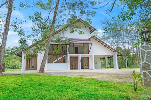 a white house with a tree at Clara Villas Amithirigala in Avissawella