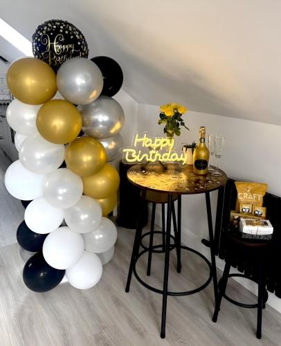 a group of balloons and a table with a happy birthday sign at Lorraine's Loft in Cookstown